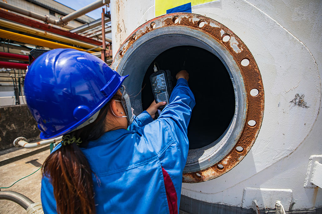Worker female hand holding gas detector inspection safety gas testing at front manhole tank chemical to work inside confined space